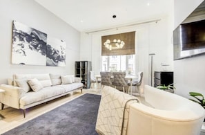 Relax in a spacious living room with a plush sofa, contemporary bathtub, and dining area.