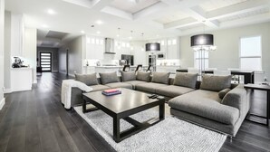 Ein modernes Wohnzimmer mit einem Ecksofa, einem Couchtisch und einem Essbereich mit einer Chandelier.
