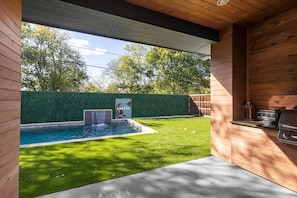 Um quintal com piscina, deck de madeira e área para churrasco.