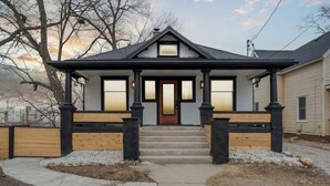 A two-story house with a front porch, a central door, and a small window above the door. - Emerald Square I 4 King Beds I 3 Bath I Loft Area (Lansing)
