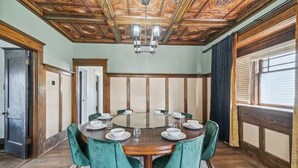 A dining room with a round table, green upholstered chairs, and a wooden ceiling with intricate designs. - Emerald Square I 4 King Beds I 3 Bath I Loft Area (Lansing)