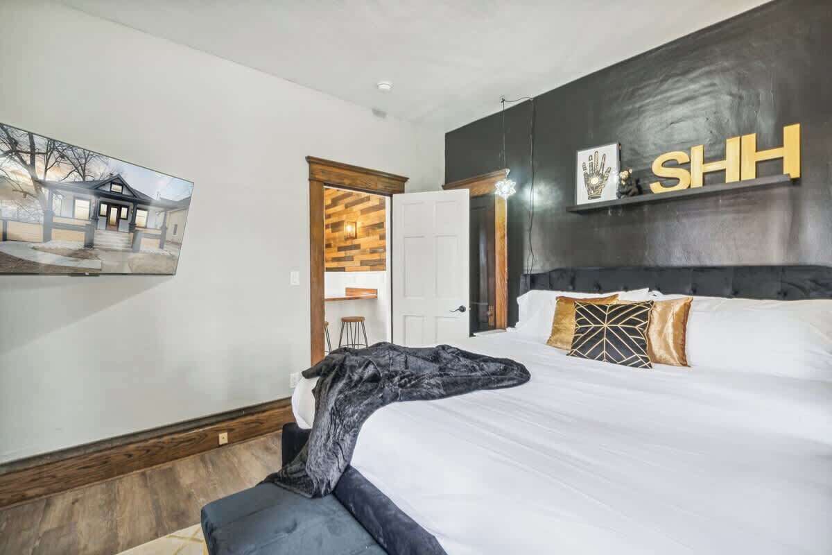 A bedroom with a large bed, a wooden headboard, and a wall-mounted shelf with a sign.