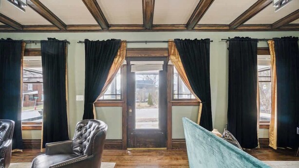 A room with a wooden ceiling, a door with curtains, a leather chair, and a teal sofa. - Emerald Square I 4 King Beds I 3 Bath I Loft Area (Lansing)