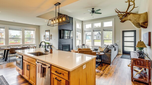 A spacious kitchen with a large island, wooden cabinets, and a ceiling fan. - Stylish Montana Vacation Rental w/ Private Hot Tub (Red Lodge)
