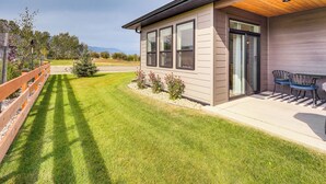 A modern house with a covered patio, a well-maintained lawn, and a wooden fence. - Stylish Montana Vacation Rental w/ Private Hot Tub (Red Lodge)