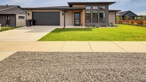 A modern two-story house with a garage, a well-maintained lawn, and a gravel driveway. - Stylish Montana Vacation Rental w/ Private Hot Tub (Red Lodge)