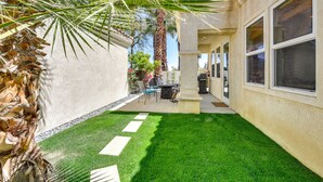 A patio area with a small lawn, a palm tree, and a building with large windows. - Pool & Hot Tub Access: La Quinta Vacation Home (La Quinta)