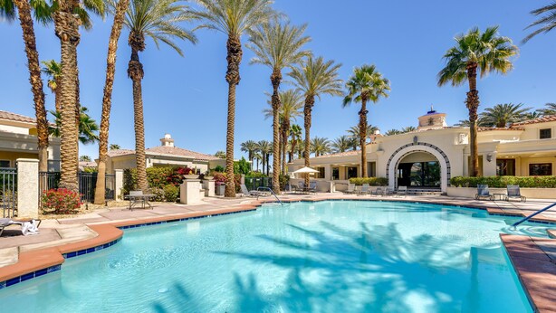 A swimming pool surrounded by palm trees and a building with a tiled roof. - Pool & Hot Tub Access: La Quinta Vacation Home (La Quinta)
