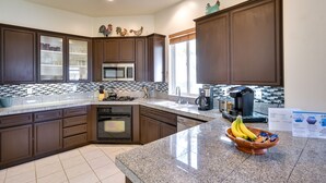 A modern kitchen with dark brown cabinets, a granite countertop, a built-in oven, and a window with a view. - Pool & Hot Tub Access: La Quinta Vacation Home (La Quinta)