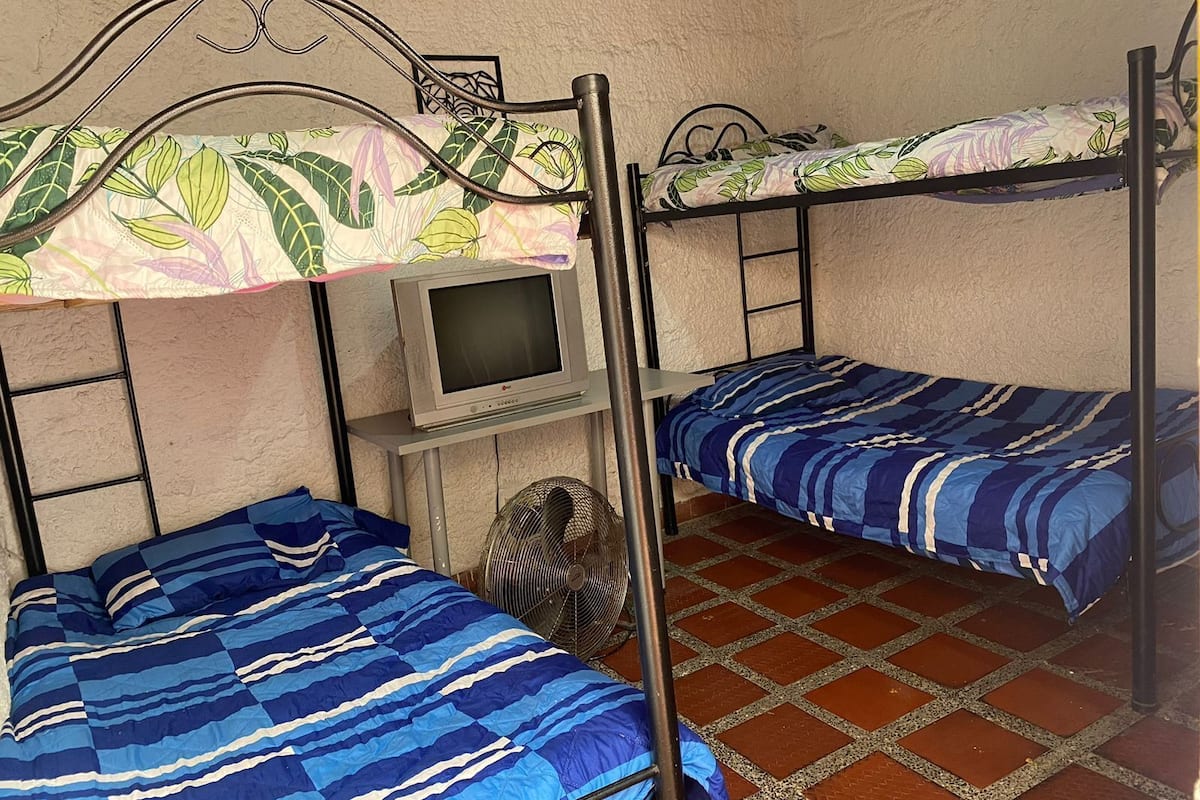 Un dormitorio con dos literas, un televisor y un ventilador.