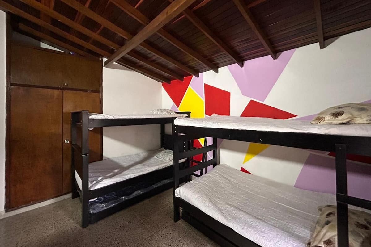 Un dormitorio con literas, una puerta de madera y un diseño geométrico y colorido en la pared.
