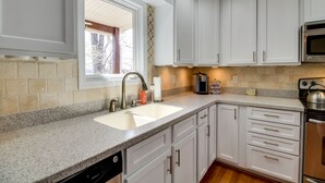 Una cocina con armarios blancos, encimera de granito, horno de acero inoxidable y lavavajillas.