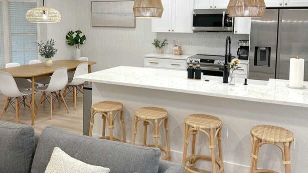 A modern kitchen with white cabinets, a central island with bar stools, and pendant lighting. - New! Beautiful Beach House, Venice (Venice)