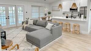 A modern kitchen with white cabinets, a stainless steel refrigerator, and a central island with bar stools. - New! Beautiful Beach House, Venice (Venice)