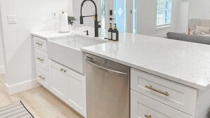 A modern kitchen with white cabinetry, stainless steel appliances, and pendant lighting. - New! Beautiful Beach House, Venice (Venice)
