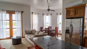 A modern kitchen with a large island, wooden cabinets, and a stainless steel refrigerator. - Brahma Blue Belize Sunset suite #7 (2Bed/2Bath) (Ambergris Caye)