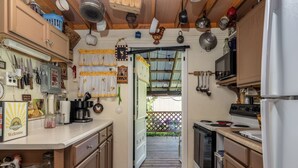 A kitchen with wooden cabinets, a stove, and a microwave. There is a door leading to a patio area with a wooden deck and a view of the outdoors.