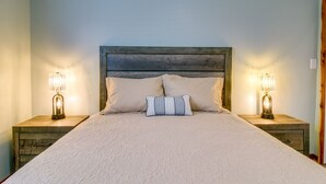 Un lit avec une tête de lit en bois, deux tables de chevet avec des lampes et un coussin à rayures.