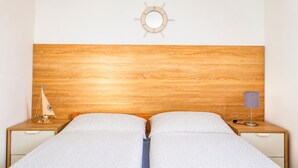A double bed with a wooden headboard, a small ship decoration, a lamp, and a wall-mounted mirror. - Nice home in Jaroslawiec with WiFi (Jaroslawiec)