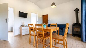 A dining area with a wooden table and chairs, a television mounted on the wall, a sofa, and a fireplace. - Nice home in Jaroslawiec with WiFi (Jaroslawiec)