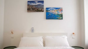 Un dormitorio con una cama, dos mesitas de noche y dos cuadros colgados en la pared.