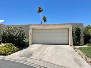 Situated in a sunny location, this house features a single-story design with a central garage and beautifully landscaped grounds.