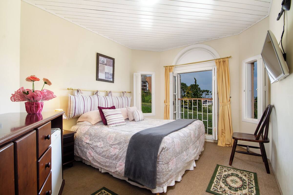 Un dormitorio con cama, cómoda y televisor montado en la pared.