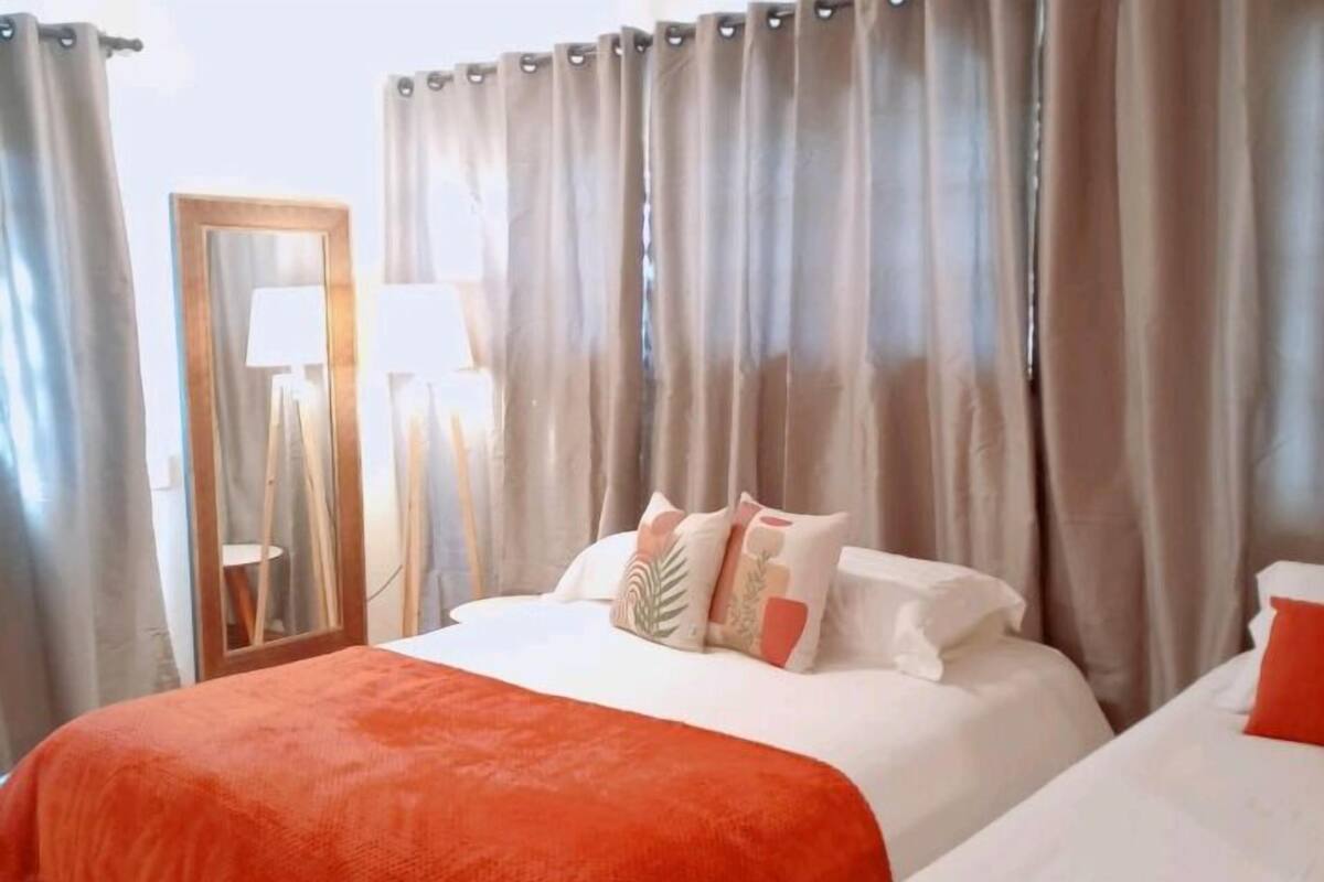 Habitación de hotel con una cama grande, una cama más pequeña y un espejo.