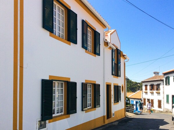 Un edificio blanco con persianas negras y detalles en amarillo.