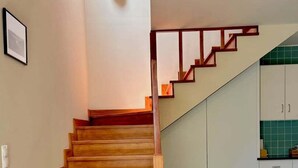 A wooden staircase leading to a kitchen area with white cabinets and a green tiled backsplash. - Casa dos Pais - Garden & Lake I (Ponta Delgada)