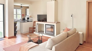 A modern living room with a sofa, a glass coffee table, a fireplace, and a television. - Casa dos Avós - Garden & Lake II (Ponta Delgada)