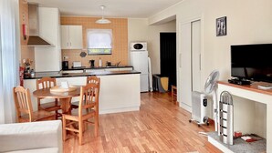 A compact living space with a kitchen, dining area, and a TV. - Casa dos Netos - Garden & Lake III (Ponta Delgada)