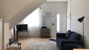 A modern living room with a dark blue sofa, a wooden coffee table, a TV, and a fan. - A house in Caloura - Blue & Beach (Caloura)