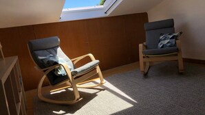 A small room with a skylight, two rocking chairs, and a wooden cabinet. - A house in Caloura - Blue & Beach (Caloura)