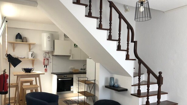 A modern living room with a staircase, a kitchen in the background, and a dining area. - A house in Caloura - Blue & Beach (Caloura)