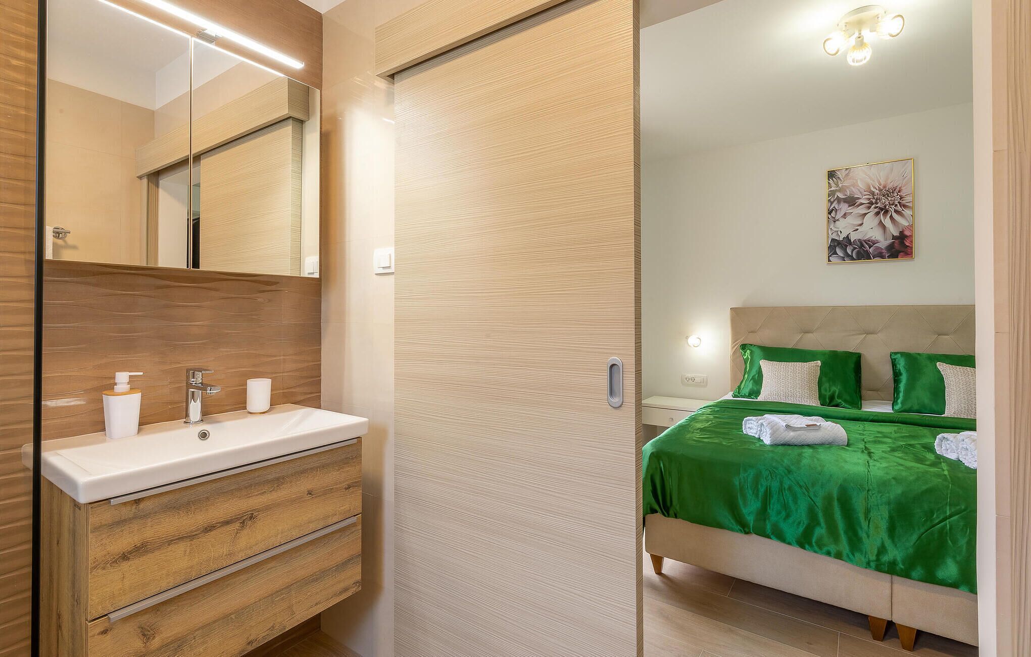 Un baño moderno con tocador de madera, un espejo y un lavamanos.