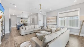 A modern living room with a sectional sofa, a coffee table, and a dining area in the background. - Luxury Beach House: Rooftop Jacuzzi & Family Fun (Inlet Beach)