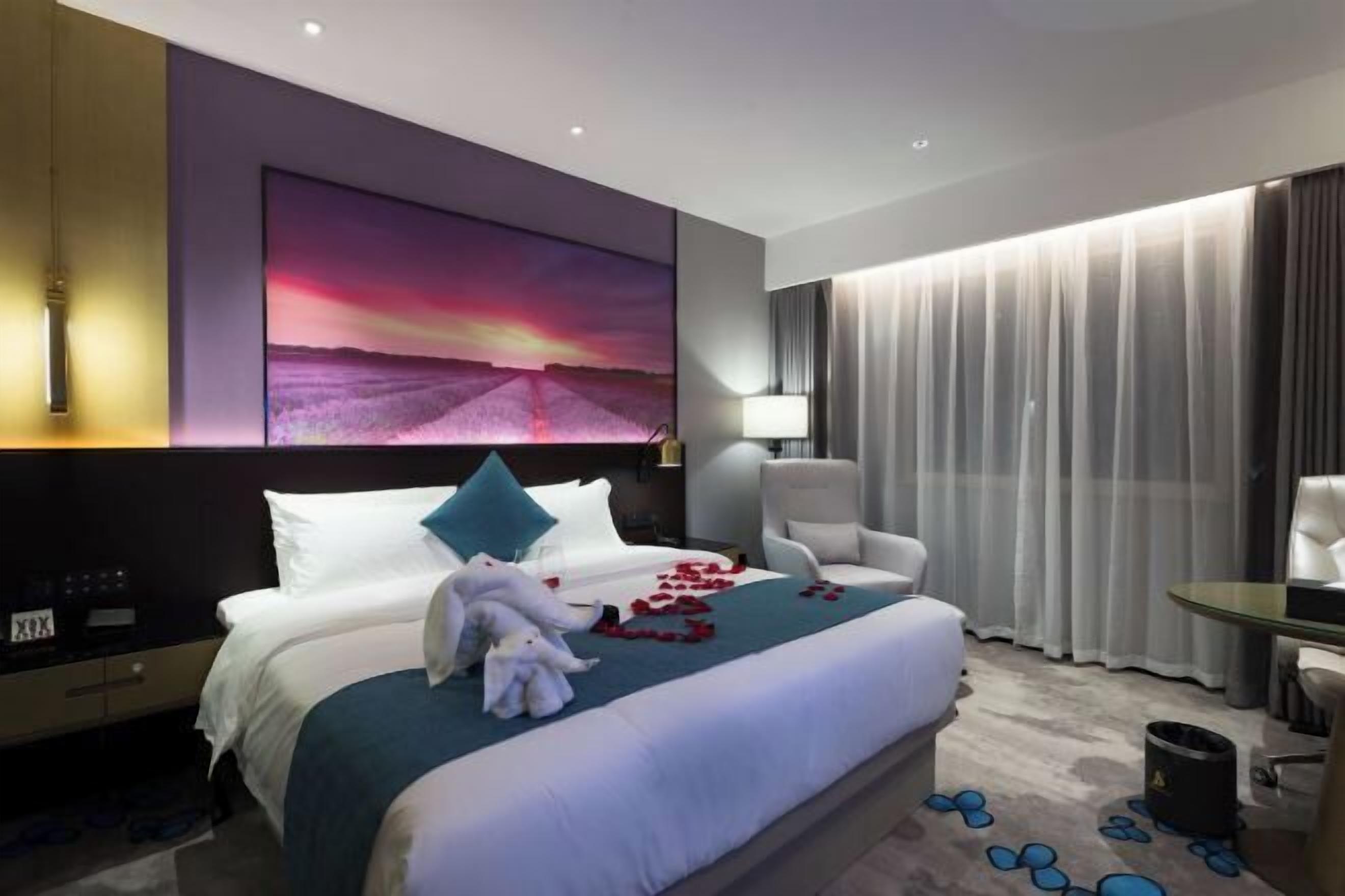 Ein Hotelzimmer mit einem großen Bett, einem Nachttisch, einem Schreibtisch und einem Sessel.