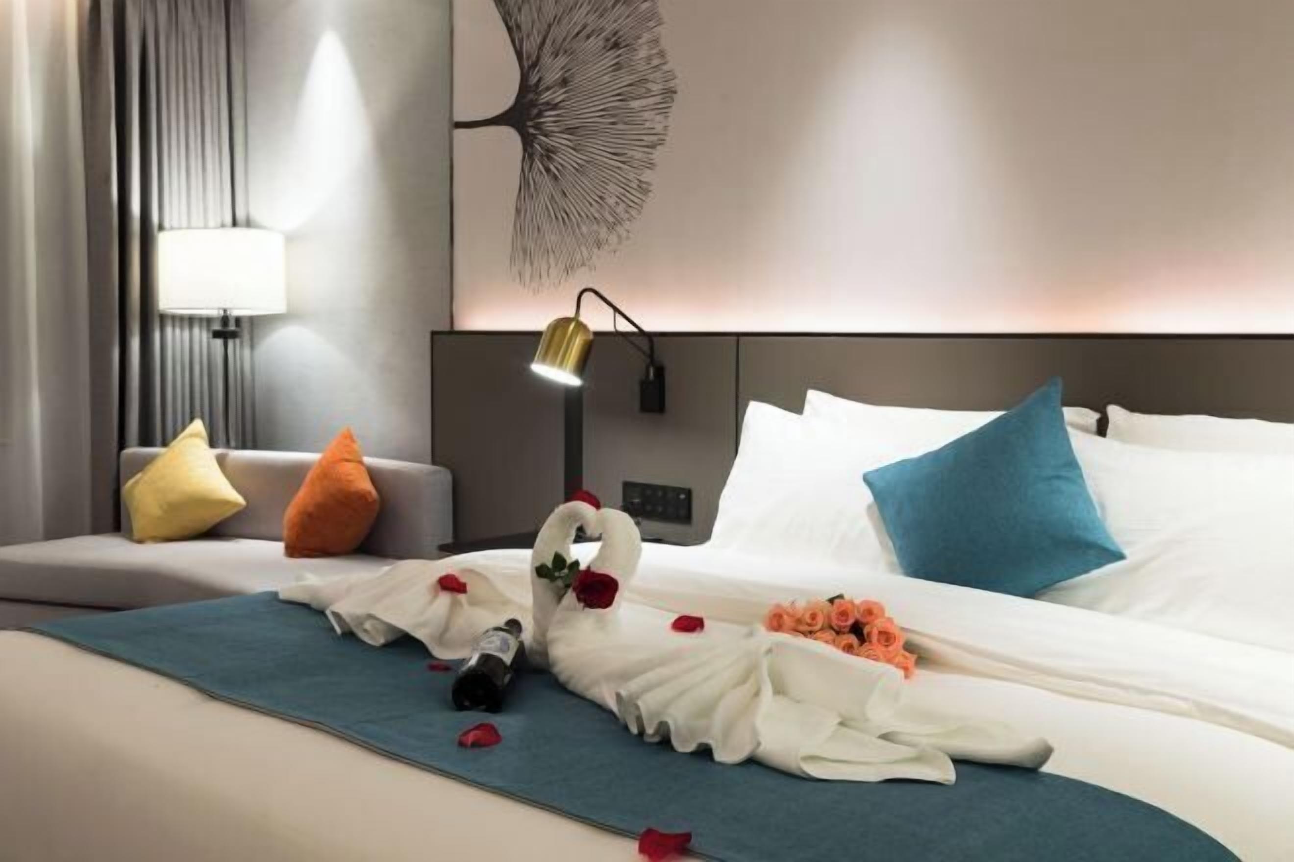 Ein Hotelzimmer mit einem Bett, einem Nachttisch, einer Lampe, einem Wandbild und einer dekorativen Schwaneinrichtung.