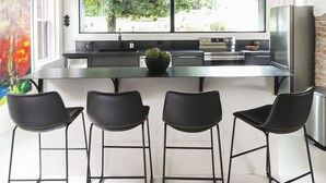 Una cucina moderna con un'ampia finestra, sgabelli da bar neri e illuminazione a sospensione.