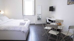A minimalist hotel room with a bed, a desk, and a chair. - APT. - Studio apartment in the historic center of Naples (Napoli)