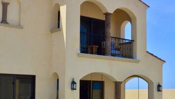 A two-story building with a swimming pool, outdoor seating, and a balcony.