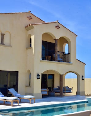 A two-story building with a swimming pool, outdoor seating, and a balcony.