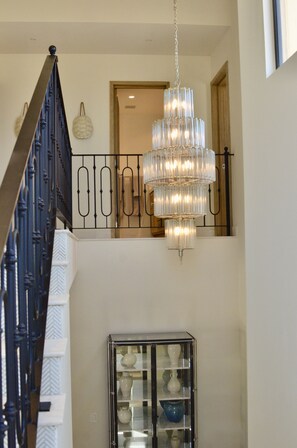 A staircase with a black railing and a chandelier hanging from the ceiling.