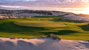 Un campo de golf con búnkeres de arena, un putting green y un marcador de bandera.