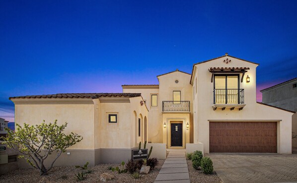 A two-story house with a garage, a balcony, and a small garden area.
