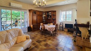 Ein gemütliches Wohnzimmer mit einem beigen Sofa, einem Esstisch mit Stühlen, einem Kamin und einem Bücherregal.