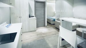 A modern, minimalist bedroom with a bed, bedside table, and a large window with blinds. - Appartamento - Angolo di Rio (Riomaggiore)