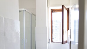 Un baño con cabina de ducha de vidrio, un inodoro y una ventana.