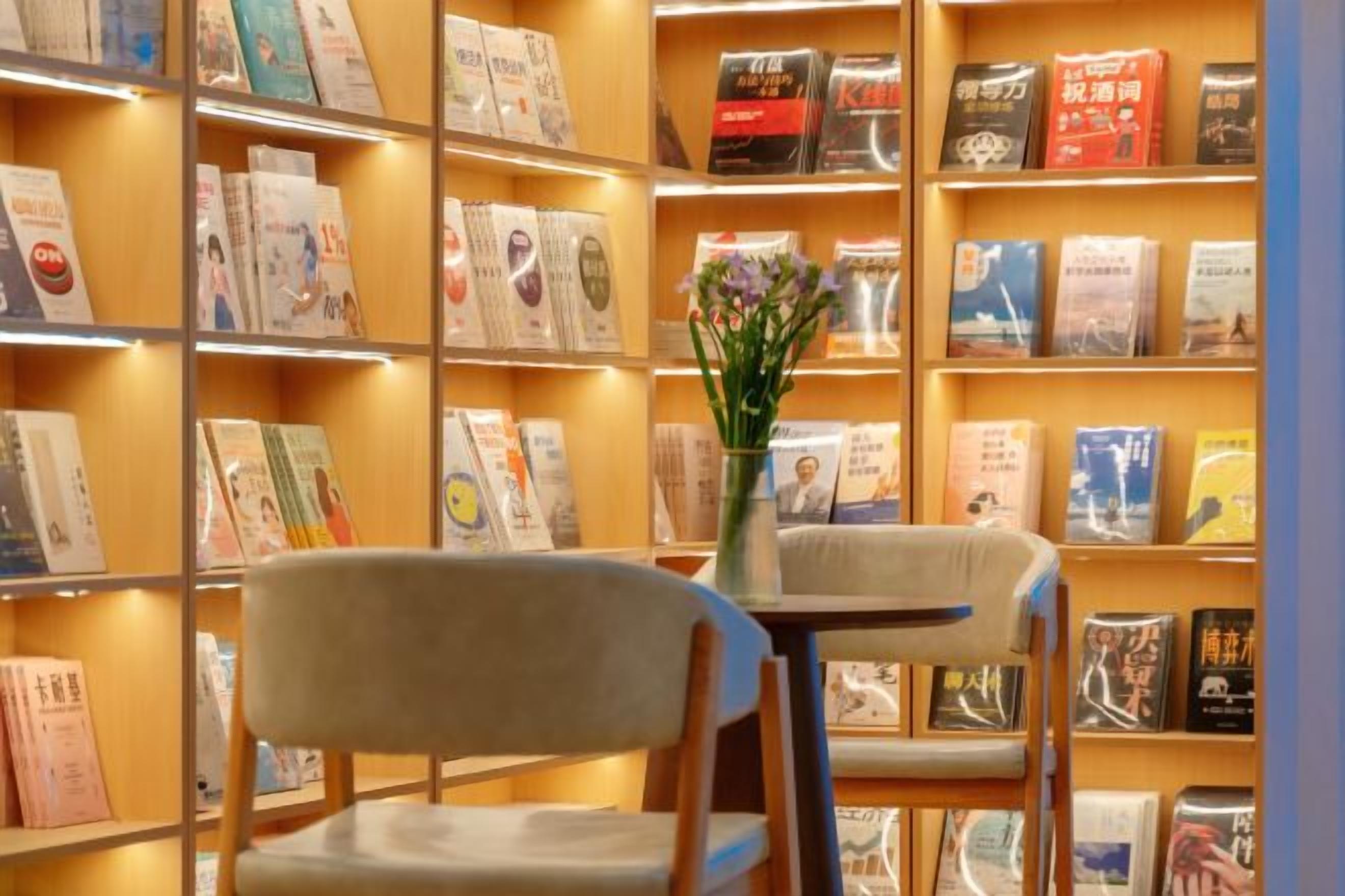 A bookshelf with books and a vase with flowers.